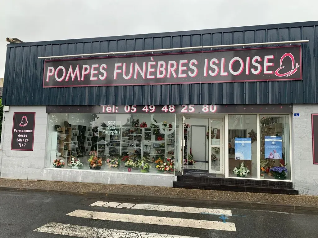 Devanture du magasin de pompes funèbres Isloise avec vitrine et enseigne lumineuse.