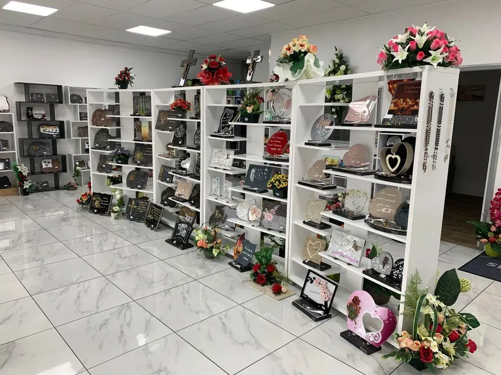 Exposition d'articles funéraires, plaques commémoratives et fleurs dans un magasin.