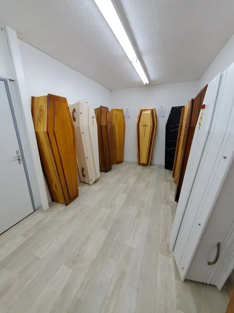 Présentation de modèles de cercueils en bois dans une salle d'exposition.